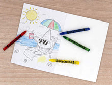 Load image into Gallery viewer, lifestyle image showing a colored page inside the book with crayons on a counter